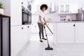 Woman Cleaning Kitchen Floor With Vacuum Cleaner Royalty Free Stock Photo