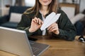 Close up of young woman doing paper plane while sitting at table with laptop and documents. Royalty Free Stock Photo
