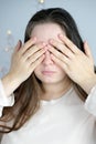 Close-up of a young woman, a girl with long hair, covering her face with her hands, the concept of awakening, hiding, not looking Royalty Free Stock Photo