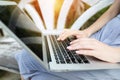 Close up young woman hands fingers press laptop keyboard for remote work on sunny day, background of sunshine green