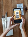 Young woman hands using the smart phone to scan the qr code to select food menu in the restaurant