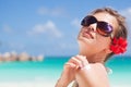 Close up of young woman with hibiscus flower in her hair and sunglasses putting sun cream on shoulder Royalty Free Stock Photo