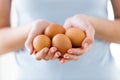 Young woman holding brown chiken eggs over white background. Royalty Free Stock Photo