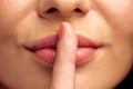 Close up of young woman holding finger on lips