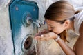 Close up of young woman hydrates herself from a fountain during a heat wave in the city Royalty Free Stock Photo