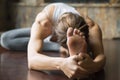 Close up young woman in Janu Sirsasana pose, home interior