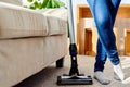 Close up of young woman in jeans cleaning carpet with vacuum cleaner in living room, copy space. Housework, household. Royalty Free Stock Photo