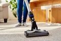 Close up of young woman in jeans cleaning carpet with vacuum cleaner in living room, copy space. Housework, household. Royalty Free Stock Photo