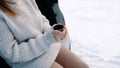 Close up, young woman leaning on the car and driniking hot beverage from the thermal bottle