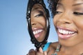 Close-up of a young woman looking at herself in mirror and smiling over colored background Royalty Free Stock Photo