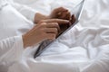 Young woman lying in bed, using computer digital tablet. Royalty Free Stock Photo