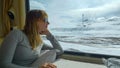 CLOSE UP: Young woman observes the scenic snowy Himalaya during a train ride.