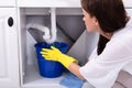 Woman Placing Bucket Under Water Leaking From Sink Pipe Royalty Free Stock Photo