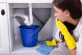 Woman Placing Bucket Under Water Leaking From Sink Pipe Royalty Free Stock Photo