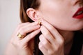 Close-up of young woman puts on gold earring. Beauty model girl in jewellery, perfect face closeup. Royalty Free Stock Photo