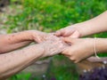 Close-up of a young woman`s hands holding an elderly female`s hands. Concept of aged people and healthcare Royalty Free Stock Photo