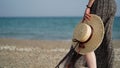 Close-up of young woman's legs and straw hat in her hand on background of sandy beach,sea,ocean,copy space. Royalty Free Stock Photo