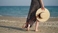 Close-up of young woman's legs and straw hat in her hand on background of sandy beach,sea,ocean,copy space. Royalty Free Stock Photo