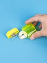 Close-up of a young woman sharpening a training slate pencil in a yellow plastic sharpener on a blue background Royalty Free Stock Photo