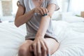 Young woman sitting on the bed while scratching her arm. Psoriasis concept Royalty Free Stock Photo