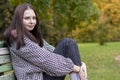 Close-up of a young woman sitting on a bench in an autumn park Royalty Free Stock Photo