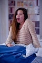 Close up of young woman with sleeplessness sitting on the bed yawning and trying to sleep, insomnia concept Royalty Free Stock Photo