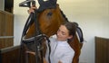 CLOSE UP: Young woman tacking up and putting a bridle on her beautiful horse. Royalty Free Stock Photo