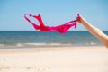 Close up of young woman taking off her bra at nude beach. Concept of sunbathing naked on the sandy ocean beach. Naturalist