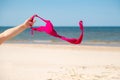 Close up of young woman taking off her bra at nude beach. Concept of sunbathing naked on the sandy ocean beach. Naturalist