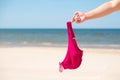 Close up of young woman taking off her bra at nude beach. Concept of sunbathing naked on the sandy ocean beach. Naturalist