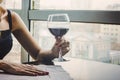 Close up of young woman which her hand holding with glass red wine as a looking out on the window. large glass of red Royalty Free Stock Photo