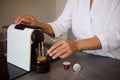 Close-up of a young woman in white bathrobe, making her morning espresso using capsule coffee machine for home use Royalty Free Stock Photo