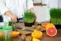 Close-up of a young woman's hands in the kitchen cutting ready-made micro-green peas for making a vitamin smoothie