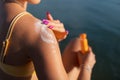 Close-up of young woman in swimsuit applying suncreen on her skin, vacation and skin protection concept.
