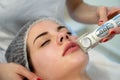 Close-up of young woman face receiving electric facial ultrusound peeling at modern beauty salon