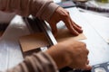 Close up of young women hands doing diy decor, cutting brown kraft paper on table, with soft natural light and casual dress Royalty Free Stock Photo