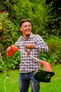 Close up of young worker wearing transparent glasses protection and holding a lawn trimmer mower cutting grass in a Royalty Free Stock Photo