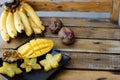 Close up yummy mango and carambola on plate near bananas on wooden table.