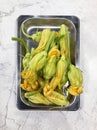 Close-up of zucchini flowers lying on a metal tray on a marble table. Cooking vegetables