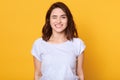 Close upportrait of positive cheerful young caucasian woman wearing white casual t shirt, blinking her eyes and looks smiling at