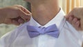 Close-ups of a man s handles corrects a blue bow tie. man dresses bow tie on white shirt. Man getting dressed for party Royalty Free Stock Photo