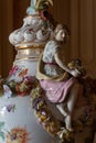 Close view of an antique ceramic decorative vase featuring a woman and garlands of flowers