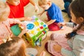 Close view of busy cube toy with kids sitting around Royalty Free Stock Photo