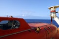 Close view on cabin of the orange colour life boat with reflective tape stickers secured with davits and safety hooks. Royalty Free Stock Photo