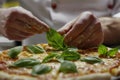 close view of a chef decorating a gourmet pizza with basil leaves Royalty Free Stock Photo