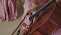 Close view of female violoncellist playing on the strings with fiddlestick