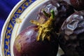 CLOSE VIEW OF GRANADILLAS IN A CERAMIC BOWL ON PURPLE CLOTH