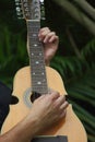 Close view of hands playing a Cuatro guitar.