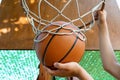 Close view of hands throwing a ball into a basketball hoop, teenage boy playing at home in the backyard, outdoor activities on Royalty Free Stock Photo