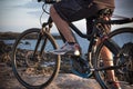 Close view of the legs of a senior man standing on the cliff with the electric bicycle. Healthy sport and lifestyle. Blue ocean Royalty Free Stock Photo